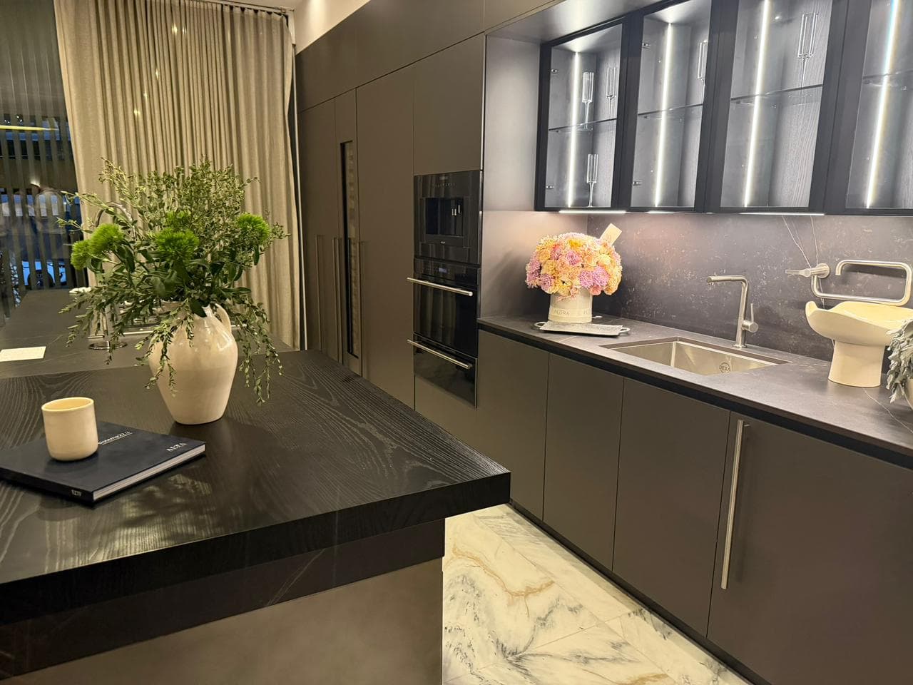 Isla de cocina oscura con arreglo de flores en primer plano