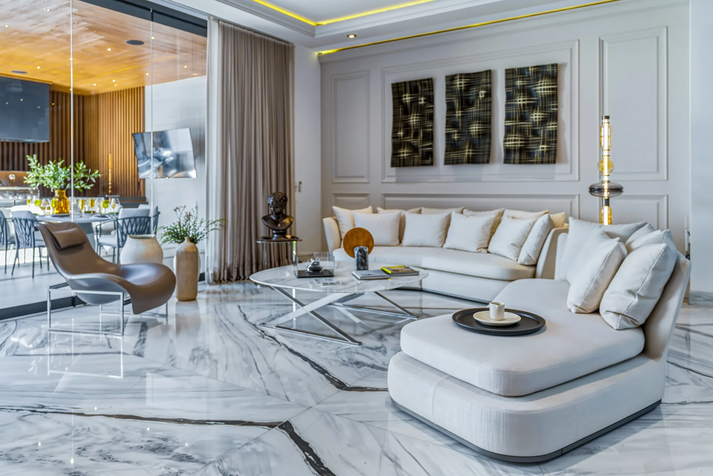 Sala con sofá modular crema y butaca de diseño sobre piso de mármol